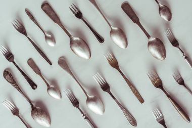 Vintage spoons and forks on white table clipart