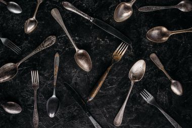 Vintage spoons and forks with knives on dark background clipart