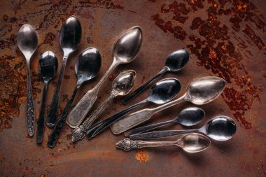 Various vintage spoons on rusted table clipart