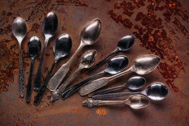 Various vintage spoons on rusted table clipart