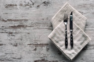 Metal fork with knife on napkin on wooden table clipart