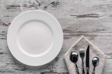 Beyaz tabak ve çatal bıçak takımı peçete ahşap arka plan üzerinde üzerinde