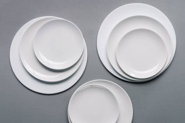 Composition of white plates on grey background clipart