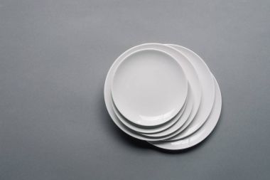 Stack of white porcelain plates on grey background clipart