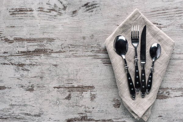Set of dinner silverware with napkin on wooden table