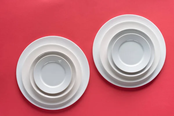 赤の背景に異なるサイズの白いお皿 — ストック写真