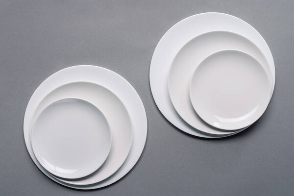 Shiny white kitchen ceramic plates on grey background