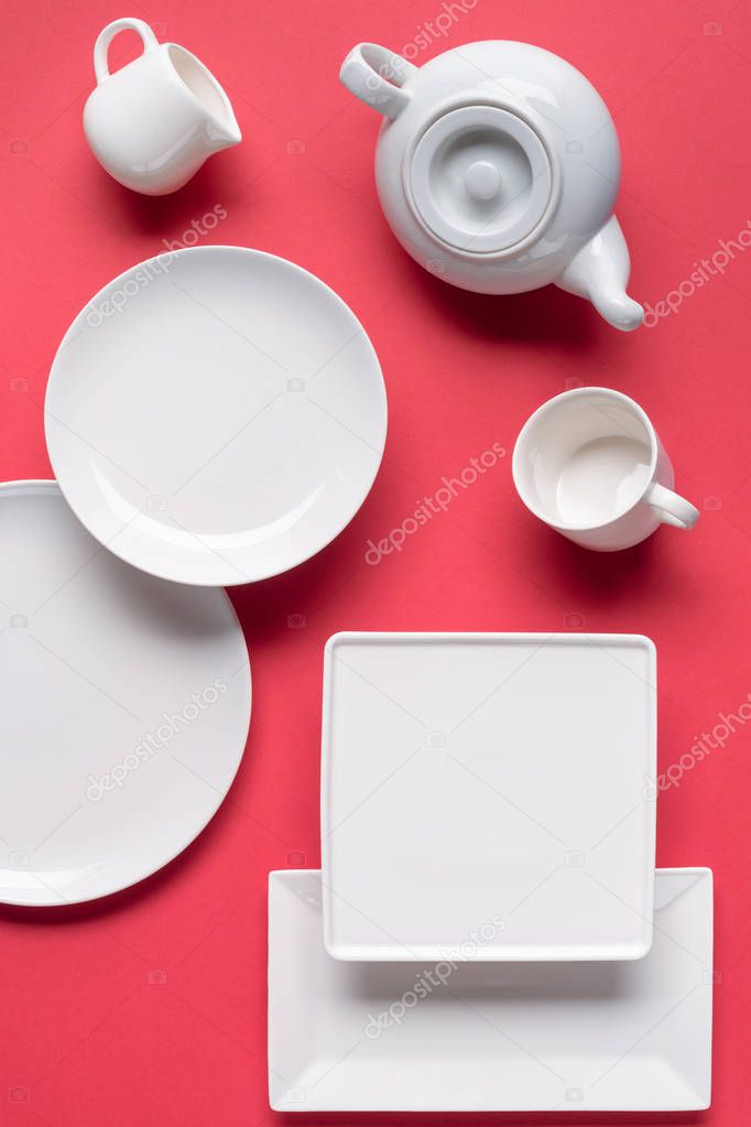 White crockery plates and tea-set on red background