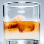 Close up view of cold iced coffee with milk in glass on grey background