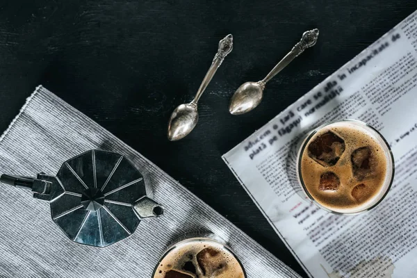 平躺在咖啡壶 报纸和眼镜的冷酿造咖啡在黑色桌面上 — 图库照片