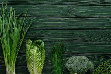 top view of green onion, broccoli and chives on wooden table, healthy eating concept clipart