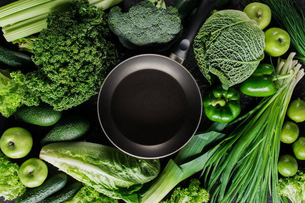 top view of frying pan between green vegetables, healthy eating concept