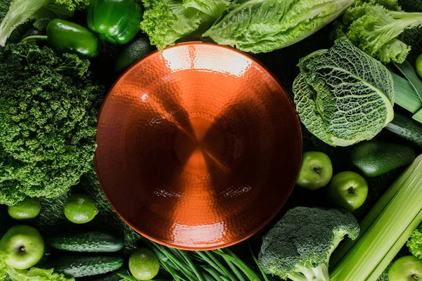 Top view of red plate on green vegetables, healthy eating concept — Stock Image Top View Red Plate Green Vegetables Healthy Eating Concept Royalty Free Stock Images