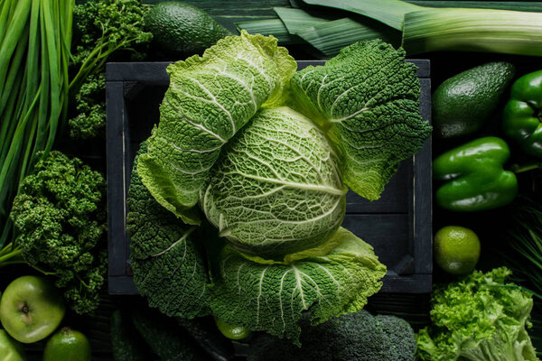 elevated view of green savoy cabbage in wooden box between vegetables, healthy eating concept