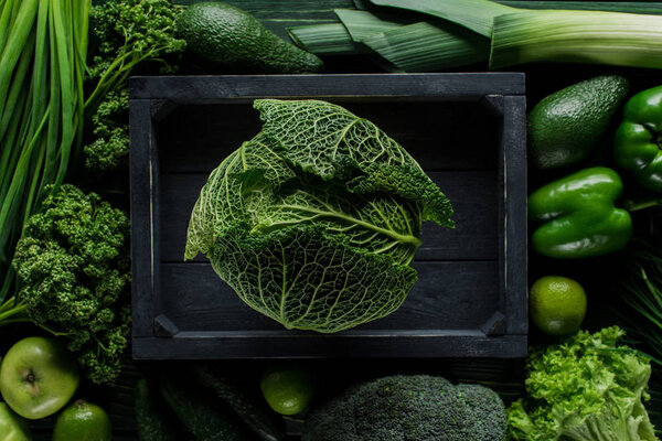 top view of green savoy cabbage in wooden box between vegetables, healthy eating concept