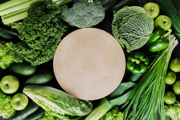верхний вид деревянной доски между зелеными овощами, концепция здорового питания
