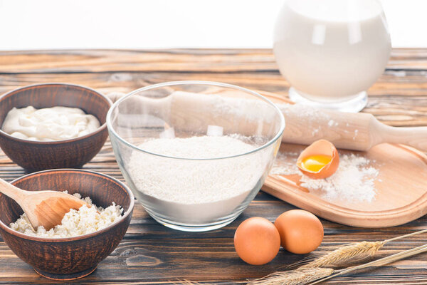 close-up view of cottage cheese, milk products, eggs and flour on wooden table  