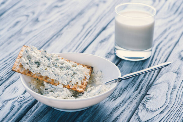 close-up view of cottage cheese in bowl, cracker and glass of milk on wooden table