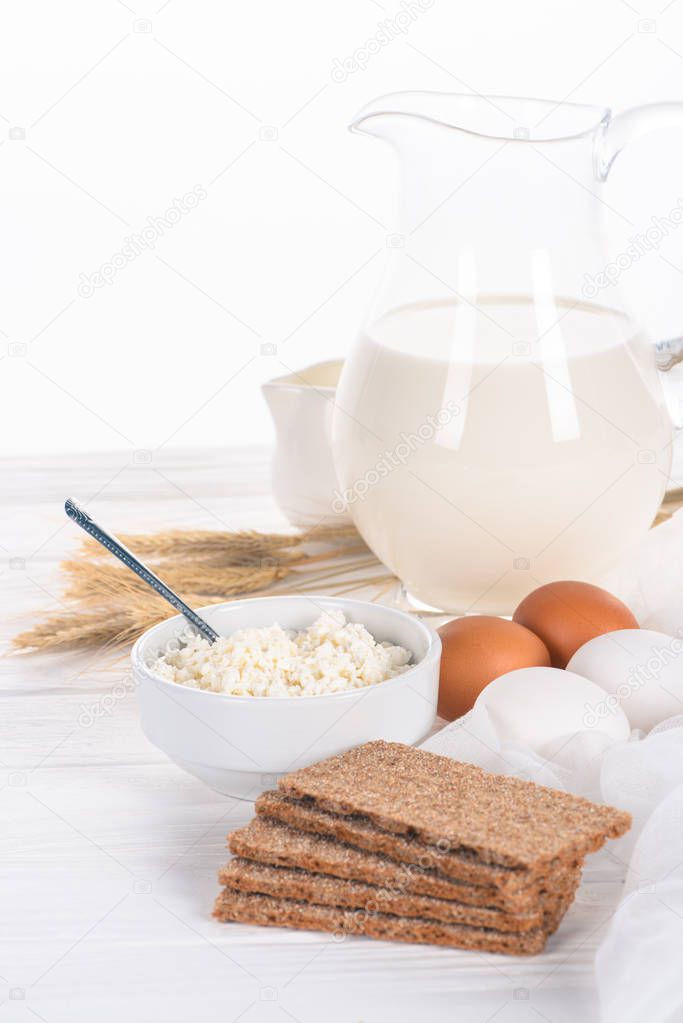 close-up view of crispy crackers, eggs, milk and cottage cheese on wooden table 