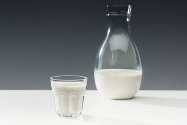 Süt cam ve şişe masanın üzerinde gri arka plan üzerinde