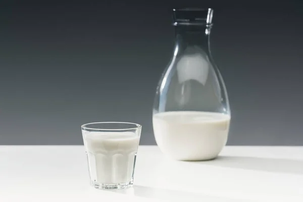 牛奶在玻璃和瓶在桌上在灰色背景 — 图库照片