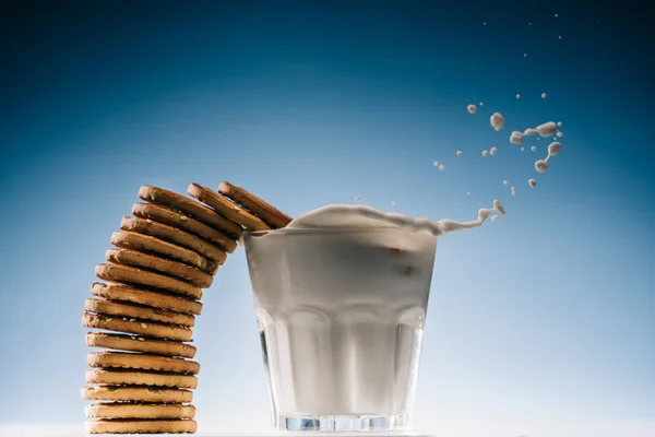 Pilha Biscoitos Salpicando Vidro Leite Isolado Fundo Azul — Fotografia de Stock