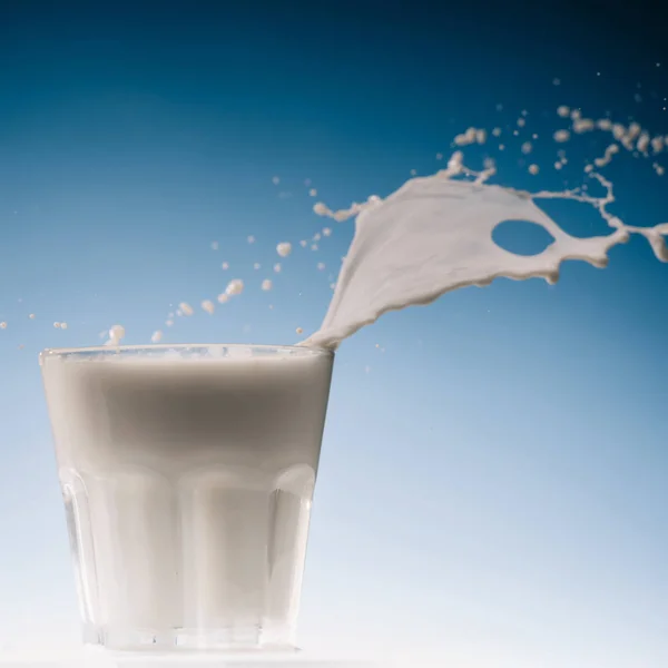 Salpicadura Grande Sobre Vaso Leche Aislado Sobre Fondo Azul —  Fotos de Stock