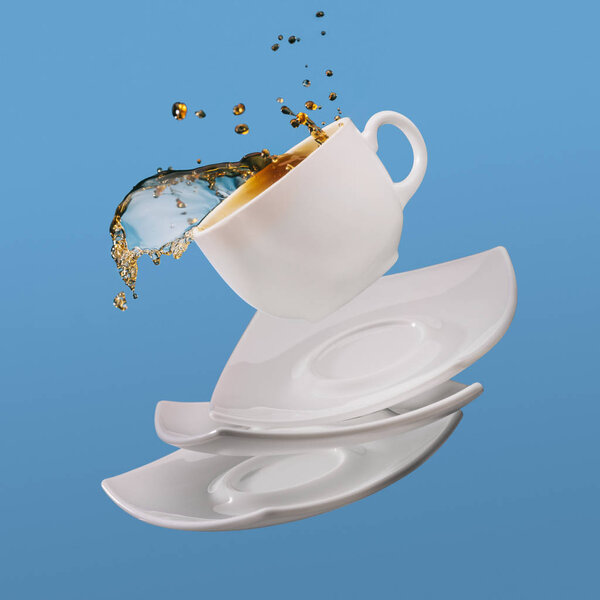 Black coffee in cup with saucers falling isolated on blue background