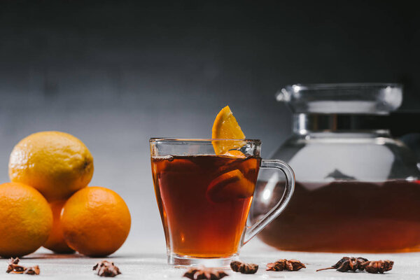 Hot black tea in cup with lemons and oranges
