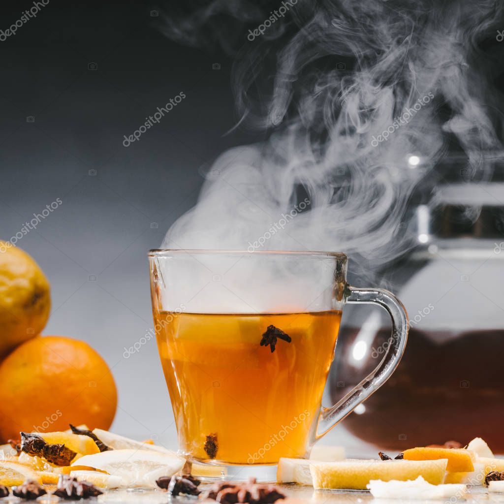 Steaming cup of hot black tea with citrus fruits