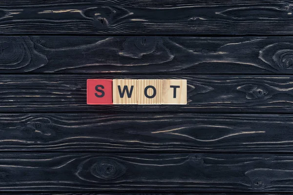 暗い木製のテーブルの上の木製のブロックで作られた単語 Swot の平面図 — ストック写真