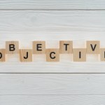 Top view of objective word made of blocks on white wooden surface