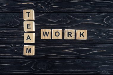 top view of team work words made of wooden blocks on dark wooden tabletop clipart