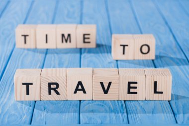 close up view of arranged wooden blocks into time to travel phrase on blue wooden surface 