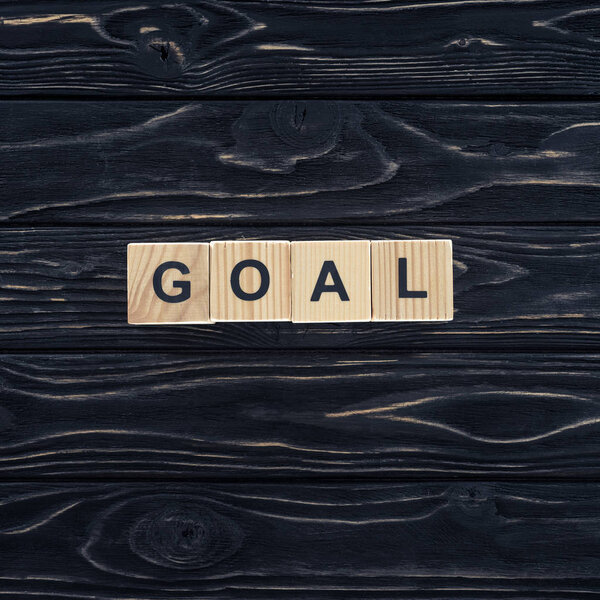 top view of word goal made of wooden blocks on dark wooden tabletop
