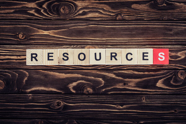 top view of wooden blocks arranged in resources word on brown wooden surface