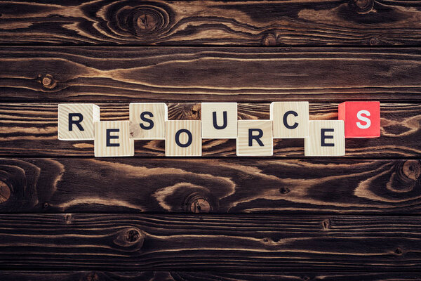 top view of wooden blocks arranged in resources word on brown wooden surface