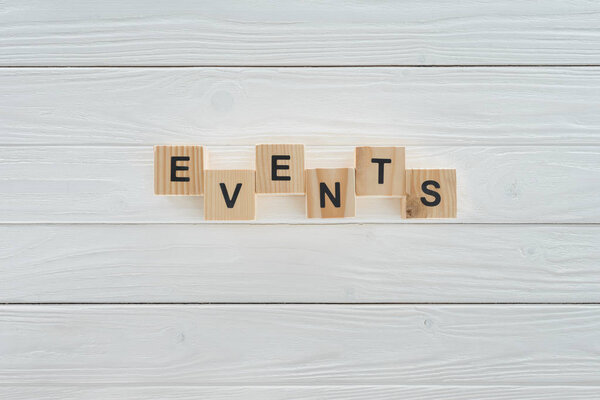 top view of events word made of wooden blocks on white wooden surface