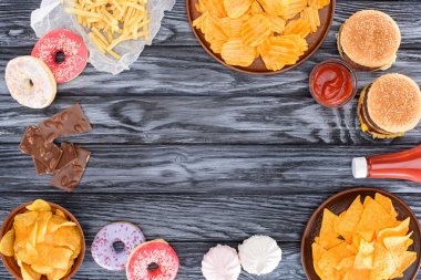 top view of assorted junk food and sweets on wooden table  clipart
