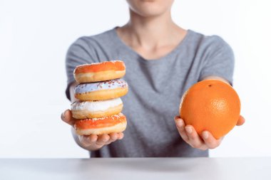 cropped shot of girl holding ripe orange and sweet donuts clipart
