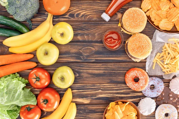 新鲜成熟水果与蔬菜和各式垃圾食品在木桌上的顶级视图 — 图库照片