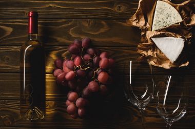şişe beyaz şarap gözlük, üzüm ve peynir ile üstten görünüm ahşap tablo