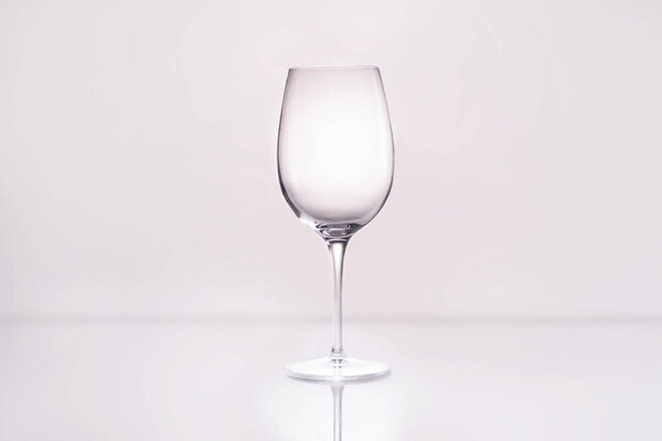 empty wineglass on reflective surface and on white