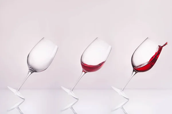 Γραμμή Κεκλιμένη Wineglasses Άδειο Και Πιτσίλισμα Κρασιού Στην Αντανακλαστική Επιφάνεια — Φωτογραφία Αρχείου