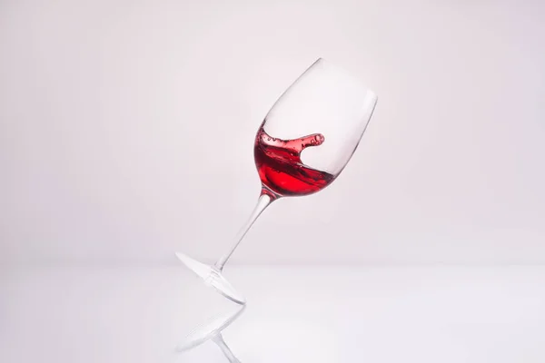 Vinho Inclinado Com Salpicando Delicioso Vinho Tinto Superfície Reflexiva Branco — Fotografia de Stock