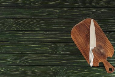 top view of knife on wooden cutting board on table  clipart