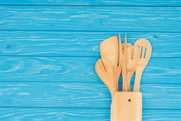 top view of different wooden kitchen utensils on blue table 