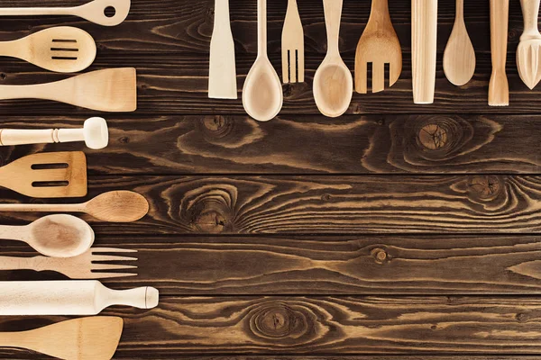 top view of kitchen utensils placed in two rows on wooden table