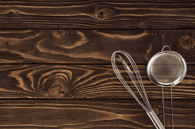 top view of whisk and sieve on wooden table clipart