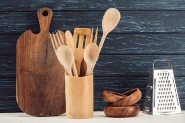 closeup shot of cutting board, kitchen utensils, grater and ramekins in front of wooden wall  clipart